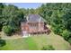 Aerial view of a red brick two-story home with a large deck, surrounded by lush green grass and mature trees at 1350 Whitley Rd, Dacula, GA 30019