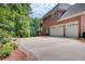 Two-story brick home featuring a two-car garage and a wide driveway, surrounded by lush greenery and landscaping at 1350 Whitley Rd, Dacula, GA 30019