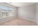 Bright bedroom featuring a large window with blinds and neutral carpet and paint at 2284 Nicole Dr, Hampton, GA 30228