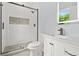 Modern bathroom featuring tiled shower with black hardware, white cabinets, and an illuminated mirror at 935 Pelham Nw St, Atlanta, GA 30318