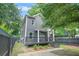 Two-story home featuring gray siding, a welcoming porch, and a fenced yard with lush greenery at 935 Pelham Nw St, Atlanta, GA 30318