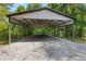 View of a metal carport with a gravel base, surrounded by trees at 12550 Hutcheson Ferry Rd, Palmetto, GA 30268