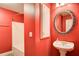 Vibrant red bathroom features a stand-alone sink, decorative mirror, shower and storage cabinet at 155 Skyview Dr, Social Circle, GA 30025