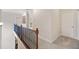 Upstairs hallway featuring wood and iron railing, carpet flooring, and access to bedrooms at 390 Scott Farm Dr, Powder Springs, GA 30127