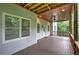 Covered back porch featuring stained ceiling, wood railing, and a view of the lush greenery at 16 Cambridge Way, Cartersville, GA 30121