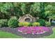 Community entrance sign surrounded by lush greenery, colorful flowers, and manicured landscaping at 16 Cambridge Way, Cartersville, GA 30121