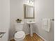 Charming powder room features a pedestal sink and decorative mirror above a toilet at 1902 Connemara Dr, Atlanta, GA 30341