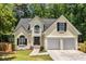 Charming home with a dark roof, a two-car garage, and mature landscaping on a wooded lot at 7167 Stonebrook Ln, Lithonia, GA 30058