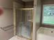 Bathroom featuring a glass-enclosed shower, tile walls, and a soaking tub near a bright window at 5415 Windcrest Ln, Suwanee, GA 30024