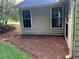 Side view of the home with two windows and landscaped yard with mulch at 5415 Windcrest Ln, Suwanee, GA 30024