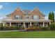 Traditional two-story brick home featuring a covered front porch and lush landscaping at 1527 Sage Ridge Dr, Marietta, GA 30064
