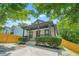 Charming home featuring a covered front porch with a ceiling fan, surrounded by lush greenery and mature trees at 556 Paines Nw Ave, Atlanta, GA 30318
