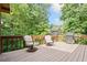Relaxing wooden deck featuring a grill and seating with views of lush backyard greenery under a blue sky at 3436 Laurelwood Ne Ct, Roswell, GA 30075