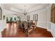 Open dining area with dark wood table, hardwood floors, and elegant decor leading into a sunlit living area at 932 Shadowford Fls, Lithonia, GA 30058