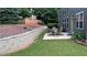 View of the home's rear exterior, featuring a table and chairs on a patio and a retaining wall at 4990 Arbor View Nw Pkwy, Acworth, GA 30101