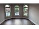 Bright living room showcasing hardwood floors and three large arched windows with views of the outdoors at 4990 Arbor View Nw Pkwy, Acworth, GA 30101