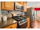 Close up of kitchen features stainless steel oven, microwave, and fridge against granite countertop and tile backsplash at 2208 Mountain Springs Nw Ct, Kennesaw, GA 30144