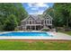 Backyard oasis featuring a sparkling pool, a spacious patio, and a two-story gray house at 9125 Patrick Pl, Winston, GA 30187