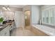Bright bathroom featuring a soaking tub, glass-enclosed shower, shuttered windows, and tile floors at 2429 Kirk Nw Ln, Kennesaw, GA 30152