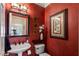 Stylish powder room featuring red walls, decorative art, a pedestal sink, and a modern toilet at 2429 Kirk Nw Ln, Kennesaw, GA 30152