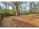 Large backyard with a mix of gravel and foliage, featuring a stone pathway and mature trees at 761 Bellemeade Nw Ave, Atlanta, GA 30318