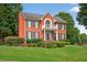Stunning two-story red brick home with a balcony and professionally landscaped front yard and manicured bushes at 2559 Dunhaven Gln, Snellville, GA 30078