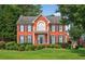 Charming red brick two-story home featuring a beautiful balcony, manicured lawn, and mature landscaping at 2559 Dunhaven Gln, Snellville, GA 30078