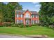 Two-story red brick home featuring a balcony, manicured lawn and bushes, with lush green trees in the background at 2559 Dunhaven Gln, Snellville, GA 30078