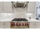 This kitchen features a stainless steel range with red knobs, marble backsplash, and custom cabinetry at 328 Stonemont Dr, Atlanta, GA 30305