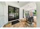 Covered front porch with stone flooring, black rocking chairs, and a view of the landscaped yard at 2166 Tanglewood Dr, Snellville, GA 30078