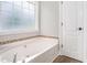 Clean, bright bathroom with a large soaking tub, tile accents, and a large window at 114 Arborwood Way, Temple, GA 30179