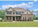 Charming two-story brick home with a covered porch, manicured lawn, and beautiful landscaping at 149 Elkins Blvd, Locust Grove, GA 30248