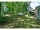 Expansive backyard showcasing the house, mature trees, greenery, and shed at 506 Bolijeri Blvd, Villa Rica, GA 30180