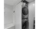 Modern laundry closet with stacked washer/dryer and storage shelf next to tub at 145 15Th Ne St # 826, Atlanta, GA 30309