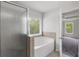 Bright bathroom featuring a shower and tub with backyard views through a window at 1618 Chancery Ln, Lithia Springs, GA 30122