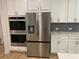 Gourmet kitchen with stainless steel refrigerator, double oven, and white cabinets with dark backsplash at 4234 Freight St, Tucker, GA 30084