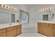 Bright bathroom with double sinks, mirrors, and a corner tub beneath a window for natural light at 629 Pine Ter, Canton, GA 30114