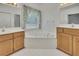 Bright bathroom with double sinks, mirrors, and a corner tub beneath a window for natural light at 629 Pine Ter, Canton, GA 30114