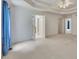 Spacious main bedroom featuring tray ceilings, a ceiling fan, plush carpeting, and bright blue curtains at 629 Pine Ter, Canton, GA 30114