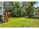 Large, grassy backyard with a deck, stairs, and mature trees at 4467 Boatmans Cv, Stone Mountain, GA 30083