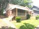 Cozy brick home featuring a covered porch, manicured bushes and mature trees at 1712 Clifton Se Way, Atlanta, GA 30316