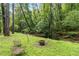 The backyard includes a firepit and seating near a stream surrounded by trees at 2200 Major Loring Sw Way, Marietta, GA 30064