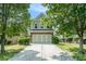 Two-story home with brick and siding, attached garage, driveway, and mature trees in the front yard at 2100 Lily Valley Dr, Lawrenceville, GA 30045