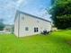 Large backyard with green grass, outdoor seating, and the back of a beige house on a sunny day at 2545 Melville Pl, Powder Springs, GA 30127
