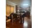 Dining area with wooden floors, a dark wood table with chairs, and a view into the kitchen on a sunny day at 2545 Melville Pl, Powder Springs, GA 30127