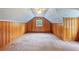Rustic attic space with wood paneling, carpet, and a small window at 357 W Hightower Trl, Social Circle, GA 30025