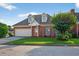 Traditional brick home with dormers above the garage featuring a pristine lawn and lush landscaping at 2000 Stockton Walk Ln, Snellville, GA 30078