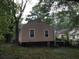 Backyard view featuring a single-Gathering home with neutral siding, surrounded by mature trees and greenery at 1566 Avon Sw Ave, Atlanta, GA 30311