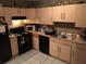 Functional kitchen with light wood cabinets, black appliances and tiled floor at 1566 Avon Sw Ave, Atlanta, GA 30311