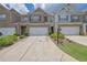 Exterior view of a well-maintained townhome featuring a one-car garage and manicured landscaping at 2638 Village Park Bnd, Duluth, GA 30096